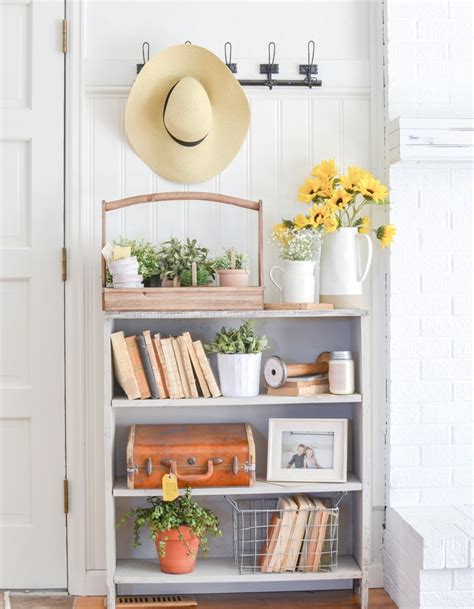 A Book Shelf With Books Flowers And A Hat On Top