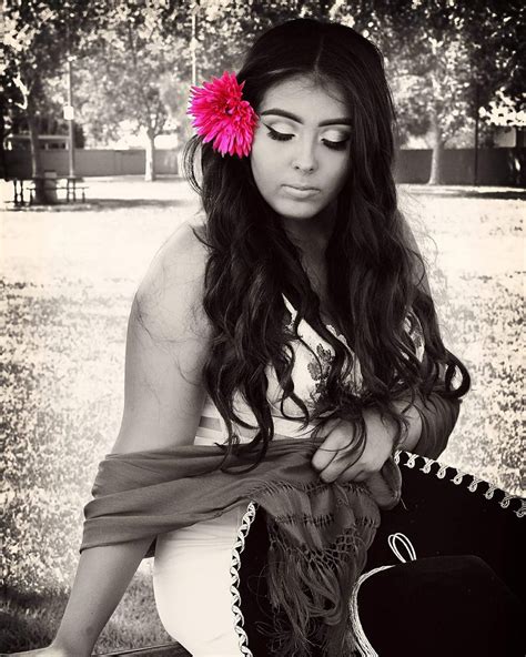 a woman sitting on the ground with a pink flower in her hair and holding a purse