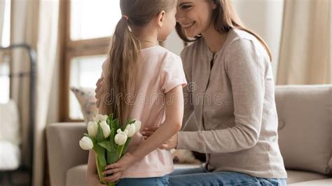Little Daughter Making Birthday Surprise For Mom Presenting Flowers
