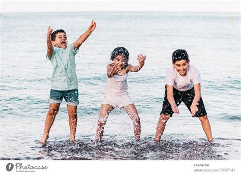 Three Kids Playing With The Water On The Beach A Royalty Free Stock