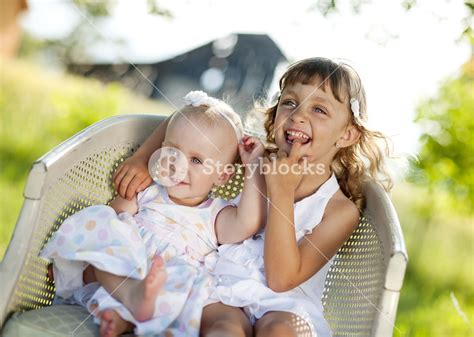 Two Cute Little Sisters Laughing And Playing In Green Sunny Park