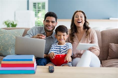 Hijo Viendo Televisión Mientras Padre Y Madre Usando Una Computadora Portátil Y Tableta Digital