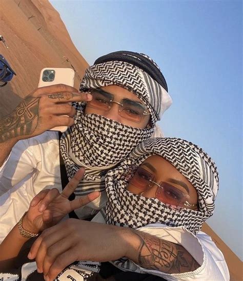 Two People Wearing Headscarves And Scarves Taking A Selfie In The Desert