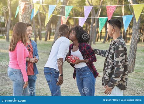 Group Of Friends Giving A Birthday Present To Their Friend While