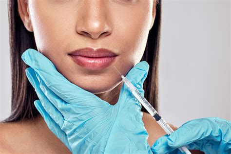 Shot Of A Woman Having Her Lips Injected With Filler Against A Studio