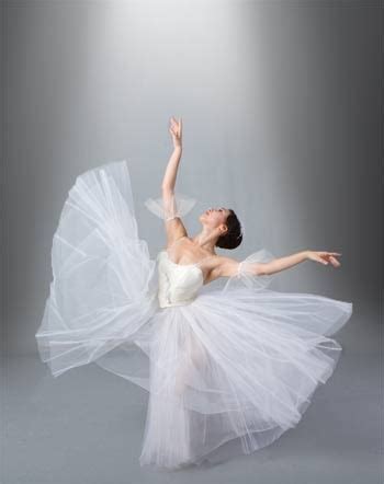 The Ballerina Is Dressed In White Tulle And Holding Her Arms Out To The Side