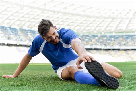 Professional Soccer Player In Blue And White Uniform Stretching On