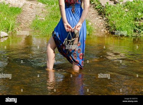 Female Legs With Blue Dress Standing Wade Into The Fast Flowing Stream