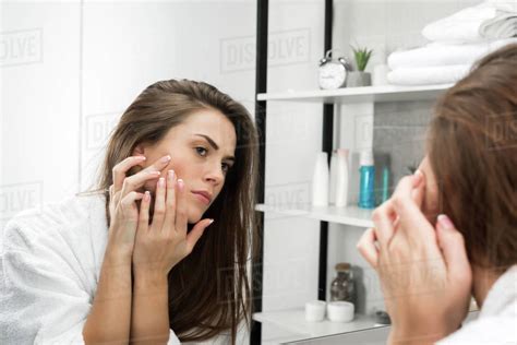 Woman Checking Face Skin And Looking At The Mirror In The Bathroom