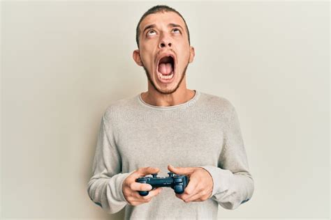 Hispanic Young Man Playing Video Game Holding Controller Angry And Mad