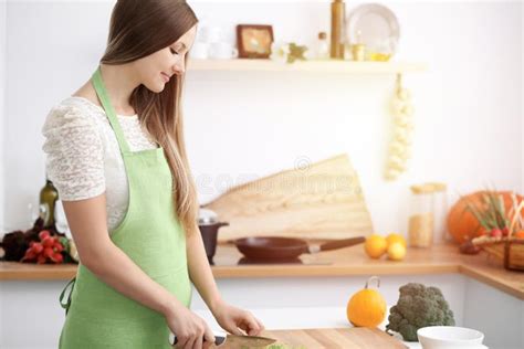 Beautiful Woman Dressed In Apron Is Cooking Meal In Sunny Kitchen Stock