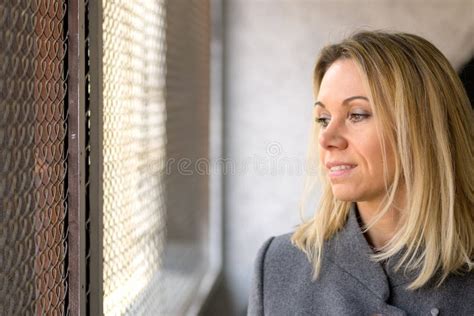Pretty Mature Woman Looking Out Of A Window With A Smile Stock Photo