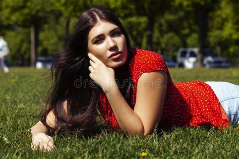 Pretty Young Woman In Red Dress Smiling Cheerful In Green Park On