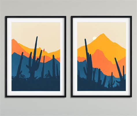 Two Framed Art Prints Depicting Mountains And Cactus Trees In Front Of