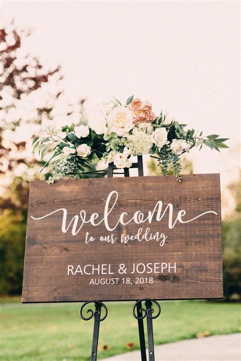 A Welcome Sign With Flowers And Greenery Is Displayed In Front Of A