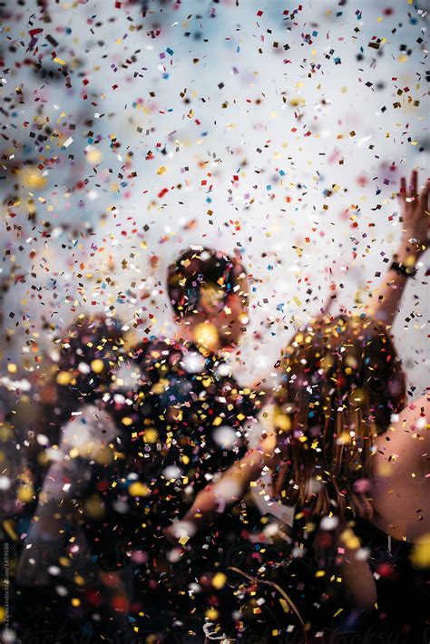 People Dancing In Colorful Confetti Rain At An Event By Stocksy