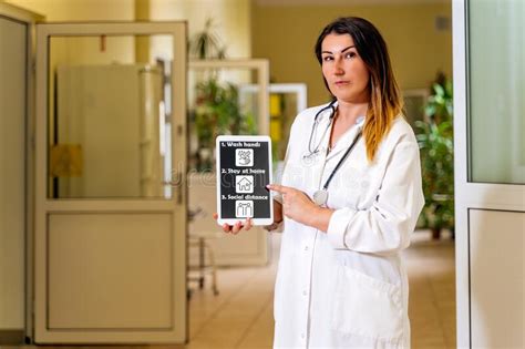 Female Doctor Standing In A Hospital Corridor With Tablet And