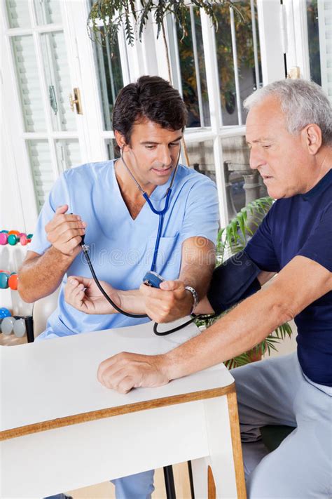 Male Nurse Checking Blood Pressure Of A Senior Stock Images Image