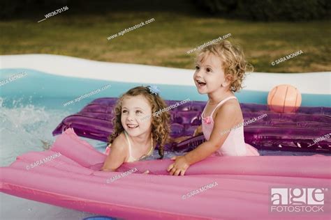 Two Happy Girls With Airbed In An Inflatable Swimming Pool Stock Photo