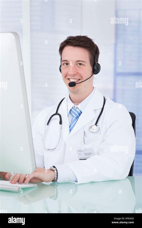 Portrait Of Young Male Doctor Wearing Headset While Using Computer At