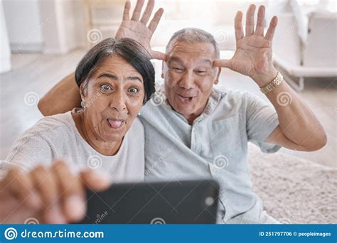 closeup of an affectionate senior couple taking selfies while relaxing in the living room at