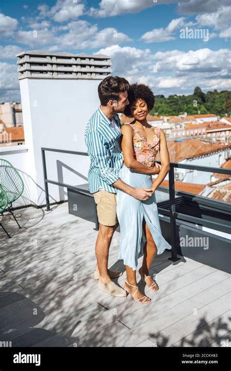 Romantic Multi Ethnic Couple Embracing On Penthouse Patio During Sunny