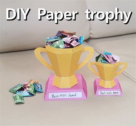Two Paper Trophy Cups Sitting On Top Of Each Other Next To Some Candy