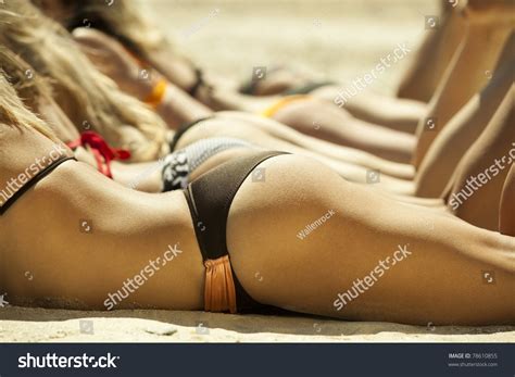 Photo Of Several Girls In Bikini Lying On Sandy Beach And Tanning In The Bright Summer Sun