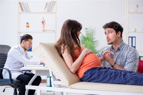 Pregnant Woman With Her Husband Visiting The Doctor In Clinic Photo Background And Picture For
