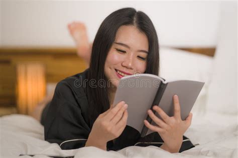 Young Beautiful And Sweet Asian Chinese Woman In Bed Reading Book Novel