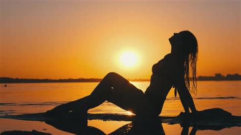 Silhouette Of Hot Woman In Swimsuit Lying And Posing On Evening Beach