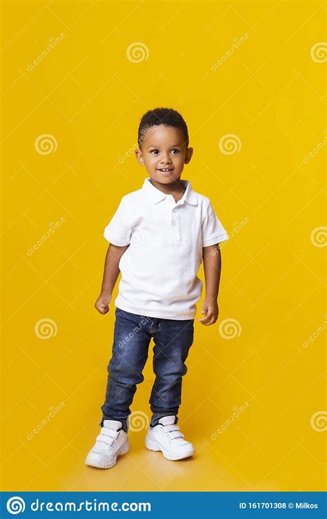 Cute Little Black Boy Standing In Studio Over Yellow