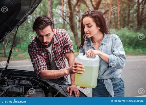 Couple Is Holding A Bottle Of Gasoline And Looking Down They Want To Fill Up Tank With Gasoline
