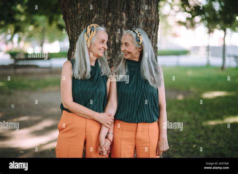 Happy Seniors Women Twins Posing In Front Of Tree In City Park