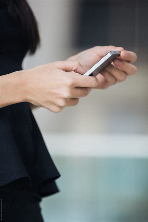 close up of hands of a businesswoman holding a mobile phone by stocksy contributor a model