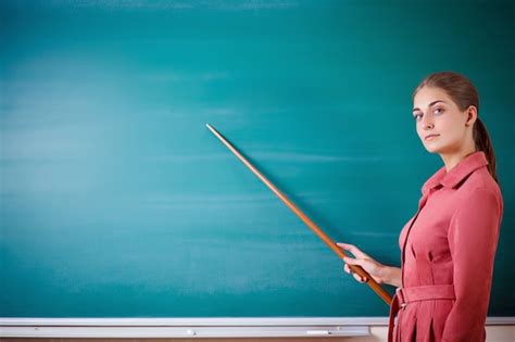 Premium Photo Young Woman Teacher Stands At A Blackboard With A Pointer
