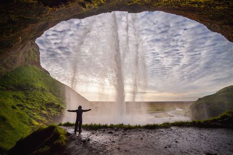 Seljalandsfoss Waterfall In Iceland Surrounded By Cliffs And Green Slopes