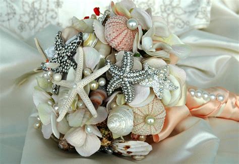 Have starfish placed in the flowers or attach mini starfish or shells to the bouquet's binding. Beach bridal bouquet brooches and shells | OneWed.com