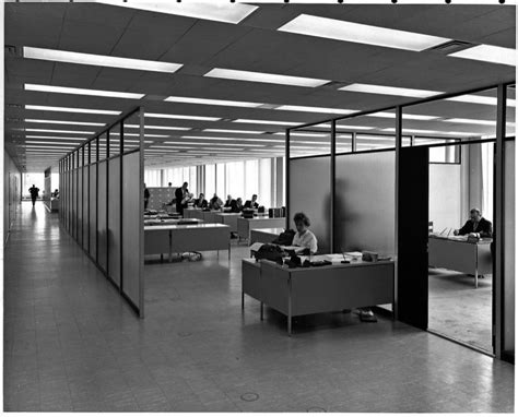 Black And White Photograph Of People Working At Desks In An Open Area