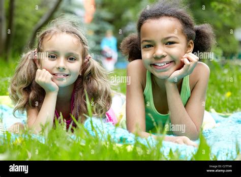 Portrait Of Two Cute Girls Having Rest In Park On Summer Day Stock
