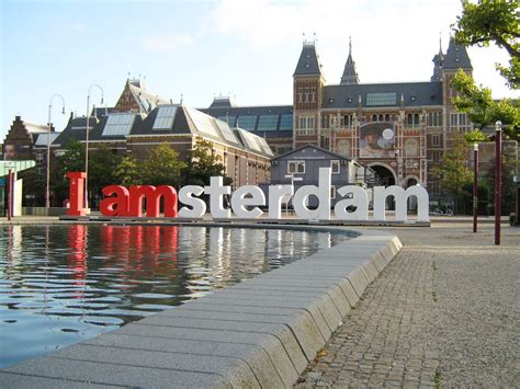 A Large Sign That Says Amsterdam In Front Of A Building With Water And