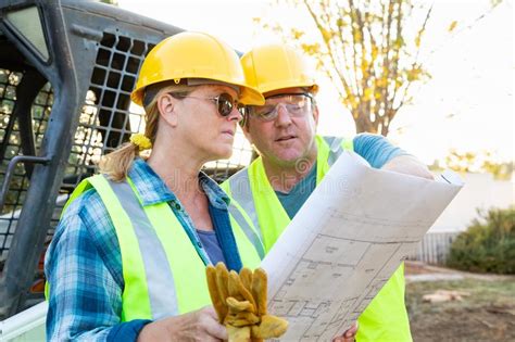 Male And Female Construction Workers With Blueprints Stock Photo