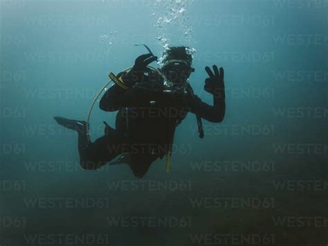 Young Man With Wetsuit And Diving Equipment Gesturing Ok Sign Under