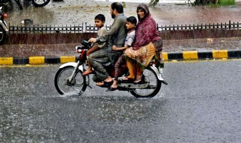 لاہور صوبائی دارالحکومت میں ہونے والی موسلا دھار بارش کے دوران ایک موٹر سائیکل سوار فیملی اپنی