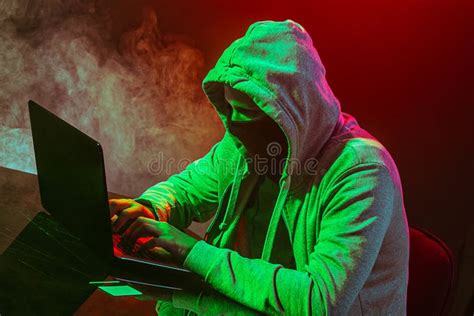 Hooded Computer Hacker Stealing Information With Laptop Stock Photo