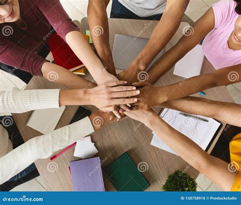 Multi Ethnic Group Of Students Joining Hands Together In Cooperation