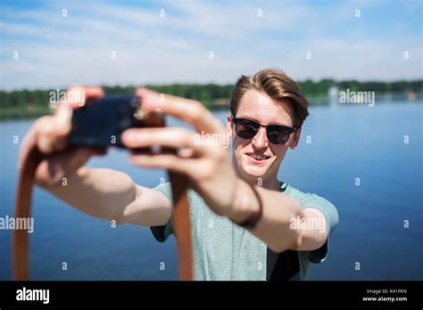 A Photo Of Young Cheerful Man Taking Himself A Photo At The Lake Stock