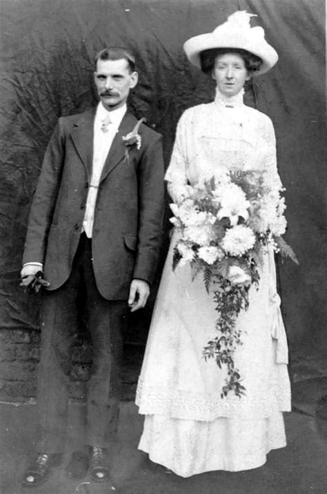 an old black and white photo of a man and woman in formal wear standing next to each other
