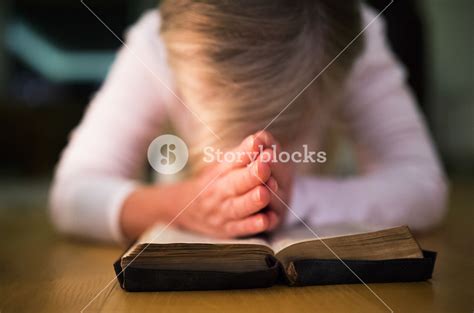 Unrecognizable Woman Praying With Hands Clasped Together On Her Bible