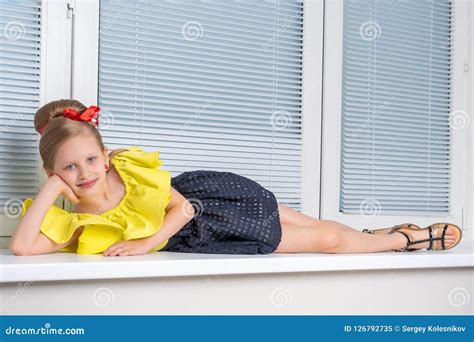 A Little Girl Is Sitting By The Window With Jalousie Stock Image